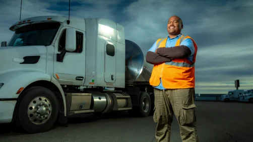 Truck driver in a safety vest beside his truck