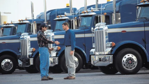 Row of semi-trucks with drivers shaking hands